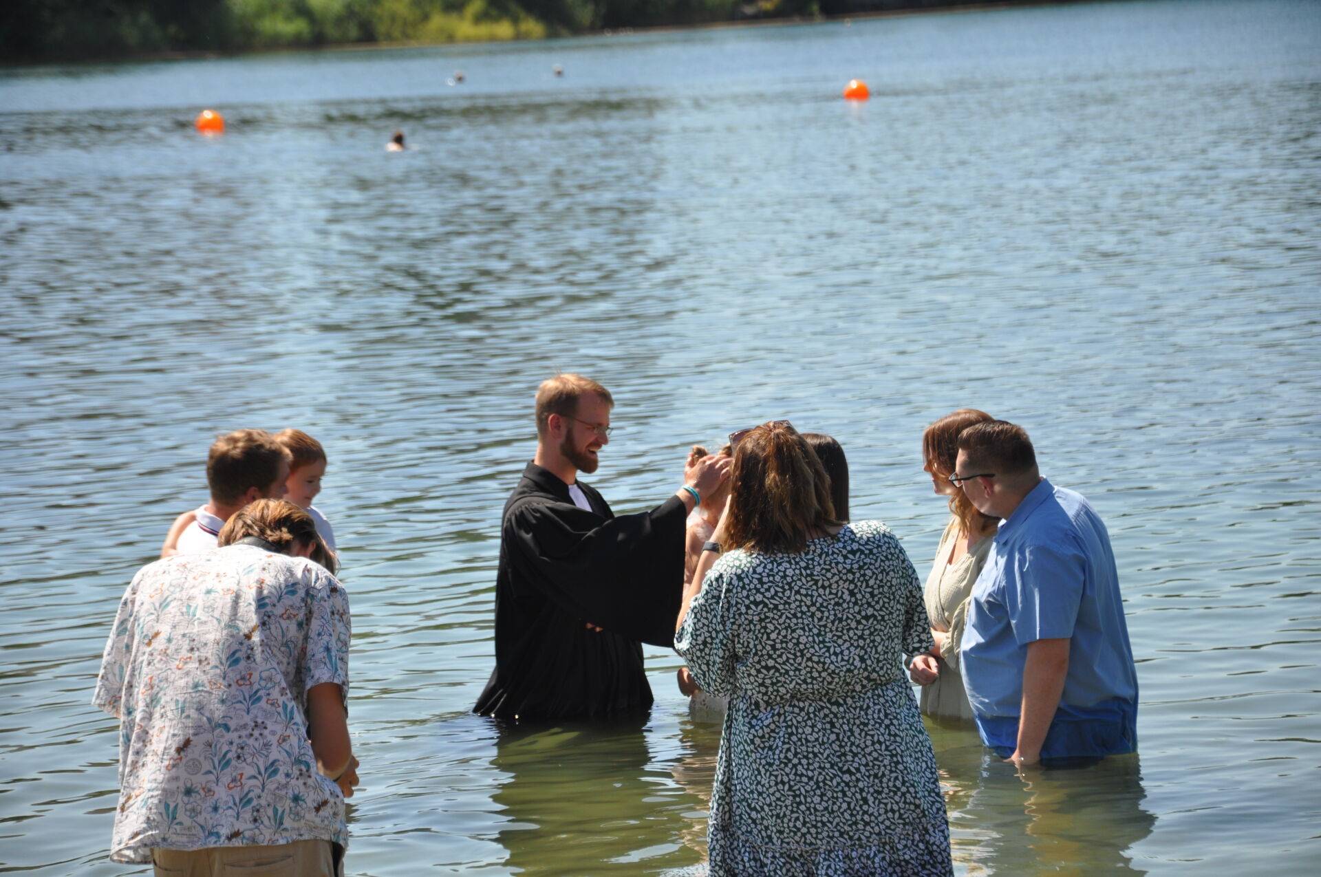 Ein Mädchen wird von Pfarrer Lukas von Nordheim beim Bensheim Tauffest 2022 im Badesee getauft.